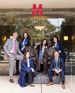 MCOB graduates in front of Abraham Mitchell statue.