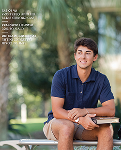 MCOB student sitting outside on bench with book in his lap.